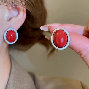 Detail of vintage red oval resin stud earrings with a matte silver textured frame