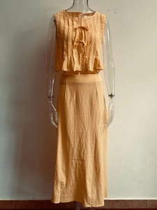 Front view of light orange cotton linen two-piece set with pleated sleeveless bow-tie top