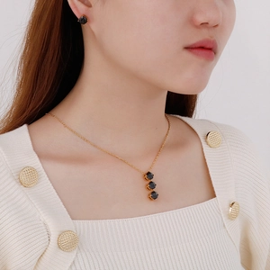 Dettaglio del set collana e orecchini dorati con zirconi neri indossati dalla modella