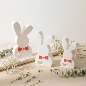 Three white rabbit statues with red bows and heart motifs for Easter home decoration