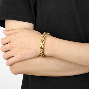 Close-up of a gold-tone dragon link chain necklace with a swivel lobster clasp on wrist