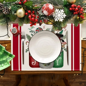 Detailed view of linen Christmas placemat with snowman and JOY print on a wooden table