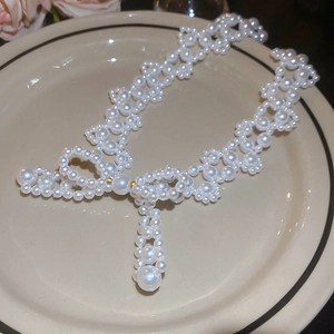 Detailed view of handmade pearl woven bow necklace on a minimalist ceramic plate