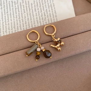 Detail view of gold-plated tiger eye stone earrings with a cute balloon dog charm