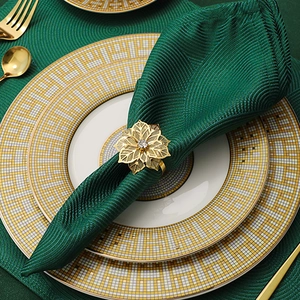 Close-up of a golden flower napkin ring with a crystal on a textured green napkin