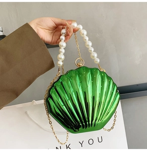 Detail of green shell clutch bag with large pearl handle and gold chain strap