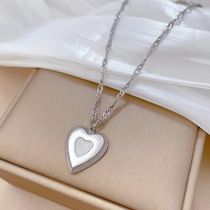 Close-up of heart pendant necklace with white inlay on soft white silk background