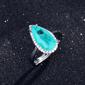 Macro shot of pear-cut paraiba blue gemstone ring with micro-pave diamonds on black band