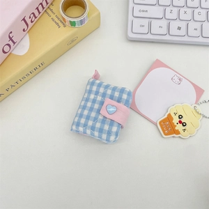 Detailed view of mini blue checkered photo album with pink heart button and fabric texture