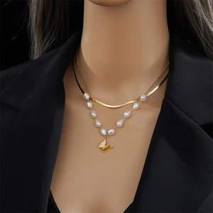 Double-layered gold pearl necklace featuring a butterfly pendant worn on a black blazer