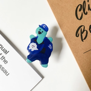 Detail of blue cartoon dinosaur brooch with Smile Dino text on paper background
