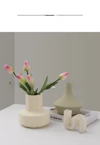 Detail of cream ceramic vases with vertical wave texture and tulips in a minimalist setting