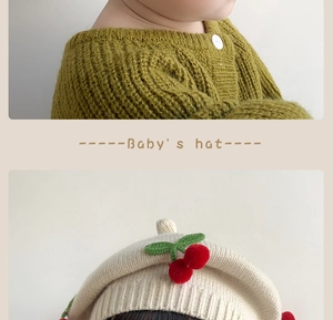 Detail of baby cream knit beret with crochet cherry and green leaf accents