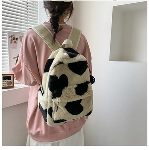 Close-up of cow print fluffy backpack featuring soft faux fur and beige straps