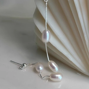 Detail of S925 silver tassel earrings with freshwater rice pearls on white shell background