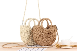 Close-up of semi-circle woven straw bags in cream and brown on a wooden table
