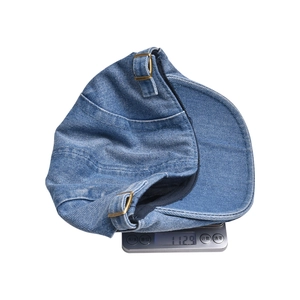 Detail shot showing the lightweight 112.9g denim newsboy cap on a digital scale