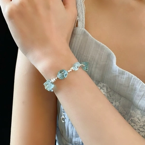 Dettaglio di un bracciale con pietre azzurre indossato al polso con accenti argentati