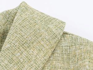 Close-up of green and yellow tweed fabric texture on a long-sleeved jacket collar