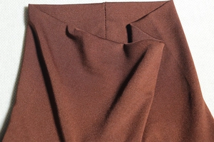 Détail de la texture du tissu élastique marron foncé et du tissage sergé de la robe