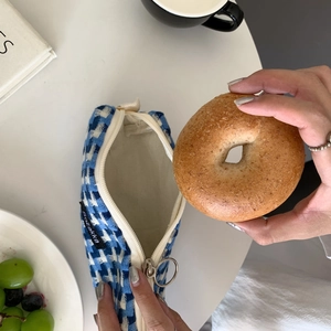 Trousse à carreaux bleu et blanc sur table avec accessoires lifestyle et café