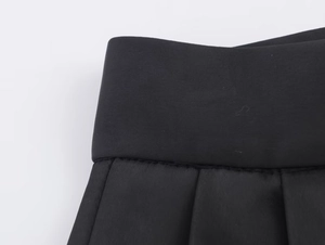 Dettaglio della cucitura in vita e trama pieghettata su pantaloni neri satinati