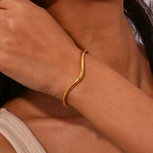 Minimalist gold stainless steel open bangle featuring elegant wavy irregular geometry