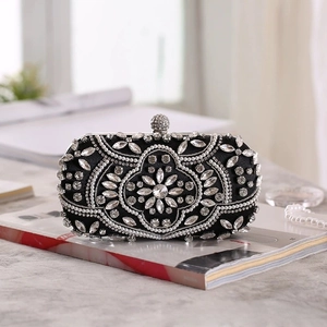 Close-up of luxury black evening clutch bag with symmetrical pearl and rhinestone flowers