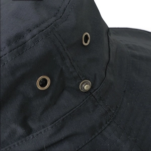 Detailed macro view of black outdoor hat with metal vents and reinforced stitching