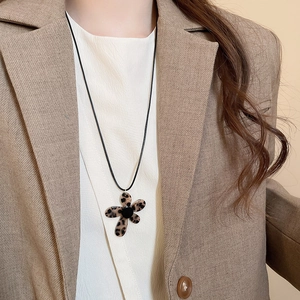 Close-up of leopard print flower pendant necklace with black cord on model