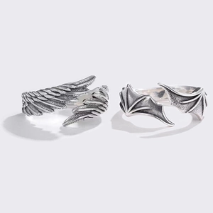 Close-up of angel and demon wing couple rings with vintage silver engraved textures