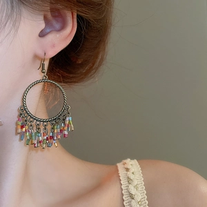 Detail of bohemian hoop earrings with colorful seed bead tassels on a model