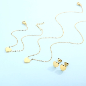 Elegant gold heart jewelry set including necklaces and earrings on blue background