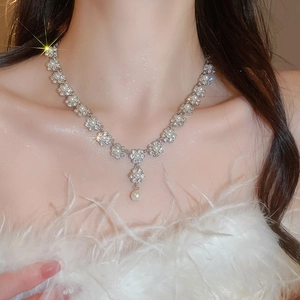 Detailed view of elegant silver floral necklace with pearls and rhinestones on a model