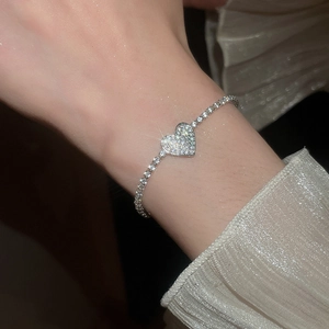 Close-up of sparkling heart charm bracelet with white zircons on a delicate tennis chain