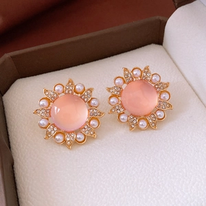 Détail macro de boucles d'oreilles tournesol avec perle rose et accents de strass
