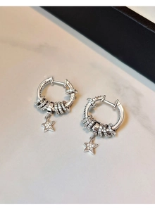 Detail shot of silver star fringe earrings with zircons on white marble surface