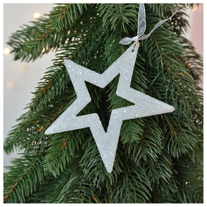 Close-up of white glittery star ornament hanging on green Christmas tree needles