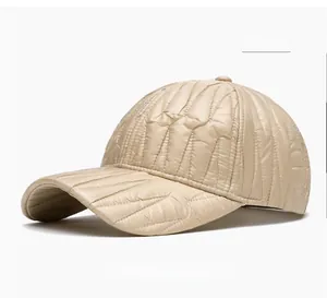 Close-up of beige baseball cap featuring quilted texture and glossy waterproof fabric