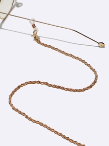 Macro detail of golden braided metal eyewear chain with clear anti-slip silicone ends