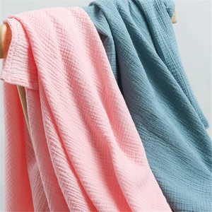 Detail of soft pink and blue cotton gauze baby hats hanging on a wooden rack