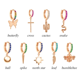 Detail view of nine gold huggie hoop earrings featuring charms like butterfly and cactus