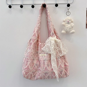 Close-up of pink canvas tote bag featuring delicate white lace embroidery and a bow