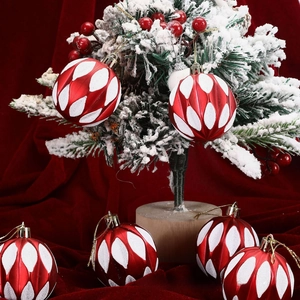 Detail of red Christmas ball with white glitter wave patterns hanging on snowy pine branch