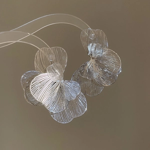 Vue macro de boucles d'oreilles fleurs argentées avec texture de pétales sur support