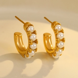 Close-up of gold-plated C-shaped hoop earrings featuring five embedded white pearls
