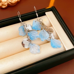 Vue détaillée des boucles d'oreilles à pompons en nacre avec charmes bleus en écrin