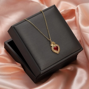 Detailed view of red heart pendant with gold crown on black jewelry box with pink silk