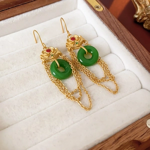 Detailed macro view of gold-plated lute lotus earrings with green jade rings and tassels