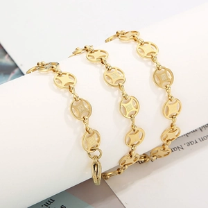 Golden stainless steel coin chain bracelet with intricate circular links on white prop